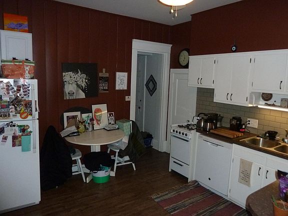 Kitchen from side entrance, BR down hall in center of photo. Pantry to left of stove, basement access is door just visible on right side of hall.