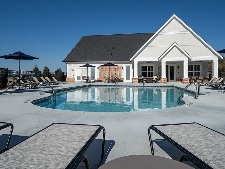 Resort-style pool with ample seating, lounge chairs and umbrellas.
