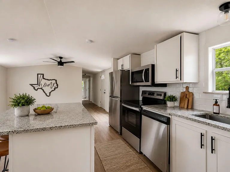 Updated kitchen with granite-look counters, stainless appliances, ample cabinetry, and an island for prep and seating.