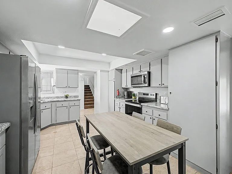 Functional eat-in kitchen with ample cabinetry, granite-look counters, and stainless appliances plus a dining table.