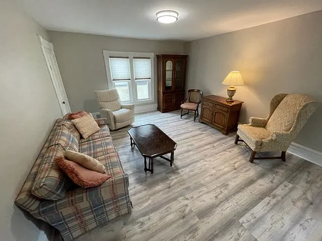 This bright and spacious living room features luxury vinyl plank flooring, large windows, and plenty of room for comfortable seating or entertaining.