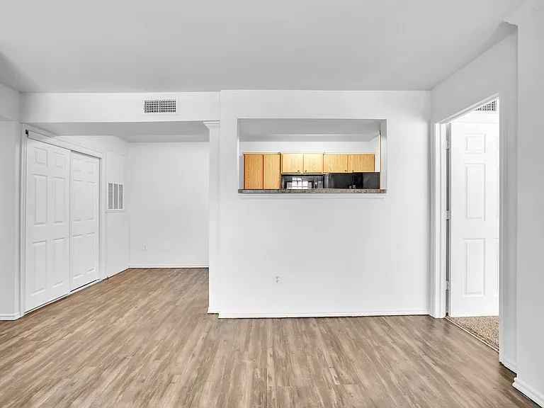 Bright apartment interior with open-concept layout, featuring a modern kitchen with wooden cabinets and sleek appliances against light-colored walls and flooring. Bright apartment interior with open-concept layout, featuring a modern kitchen with wooden c