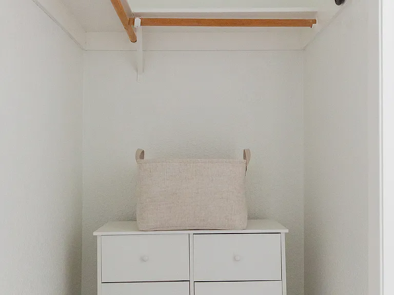 Master walk in closet with dresser, hamper and extra set of queen sheets.