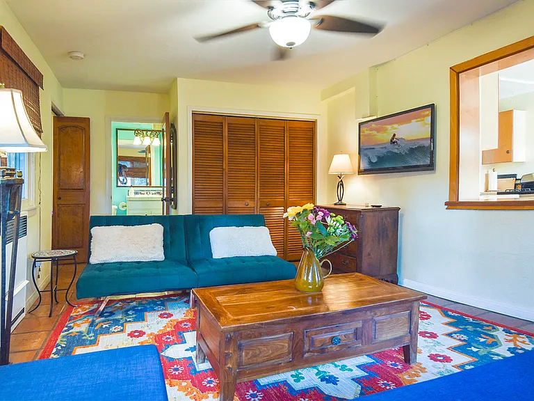 LIVING ROOM: Breakthrough to Kitchen (right), 42" HDTV (right), Bathroom (rear, center), Bedroom entrance (rear, left), Blue and Green Sofa-Beds