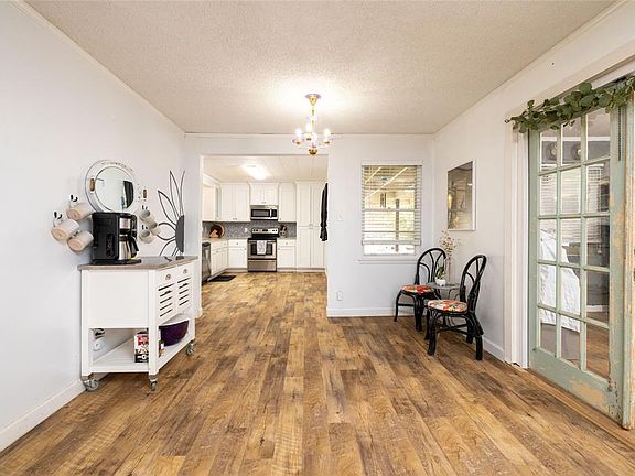 View into the dining area and eat in kitchen from the living room, with a bedroom on the right