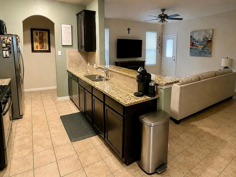 Open kitchen with granite breakfast bar, stainless appliances, and a double sink overlooking the living area.