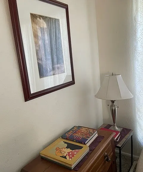Living room detail of antiques, books, and lamp.