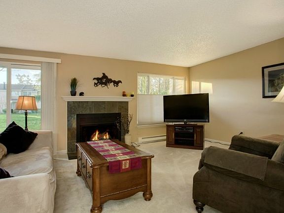Spacious living space with southern exposure! Enjoy lots of natural light, wood burning fireplace with slate surround & sliders to patio.