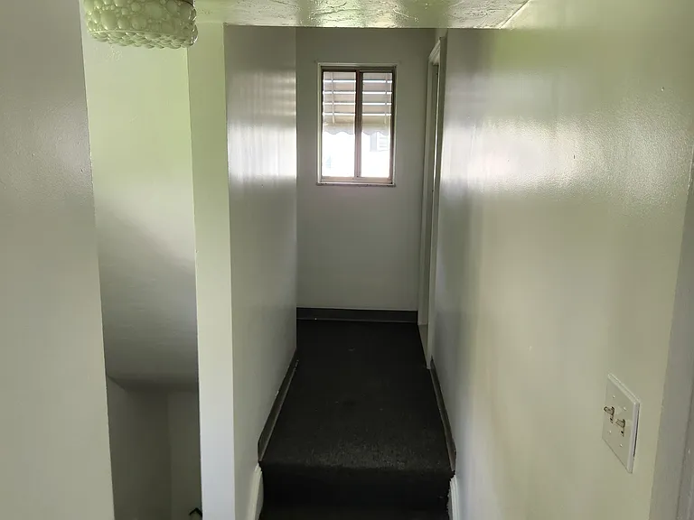 Interior Stairwells, Looking out the Upper Unit's kitchen doorway toward Living Room Doorway (end on right). Stairs down to the exterior doors and basement. New paint in the hallways.