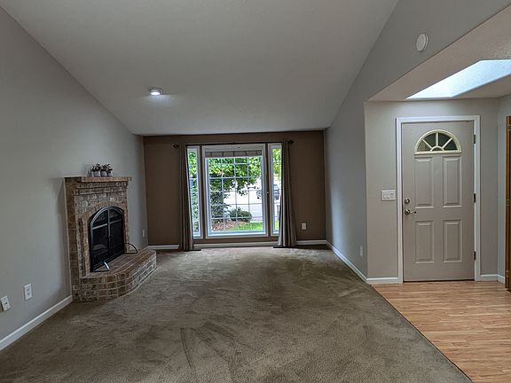 Great Room with wood burning fireplace and large front window