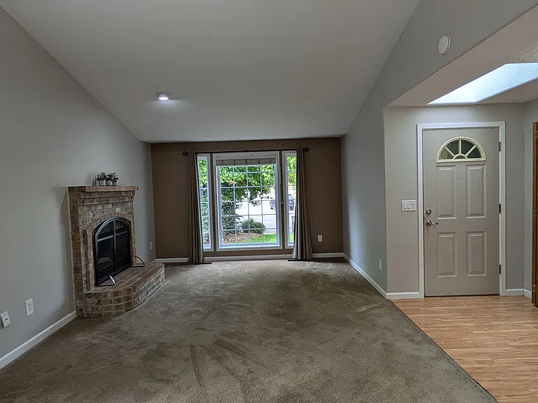 Great Room with wood burning fireplace and large front window