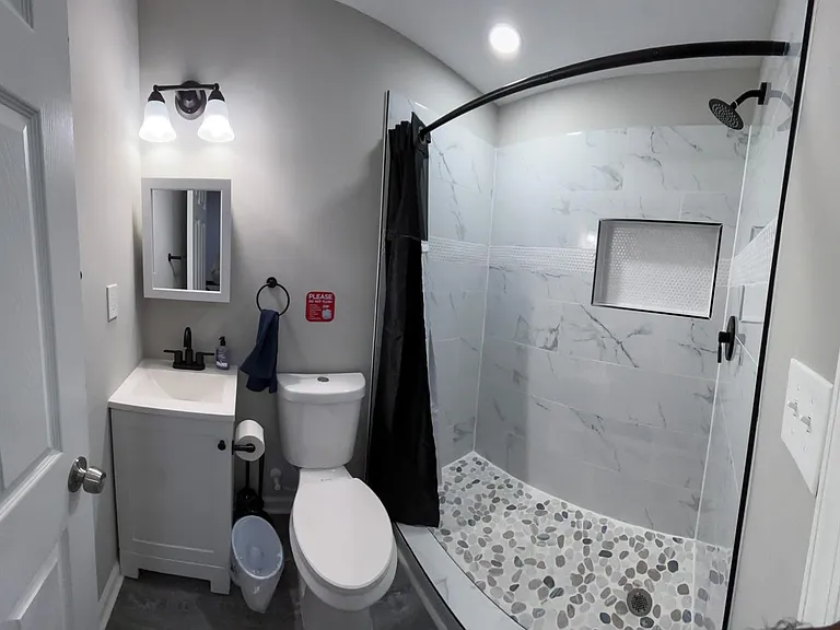Updated bathroom with a single-sink vanity, matte-black fixtures, and a tiled walk-in shower with built-in niche.