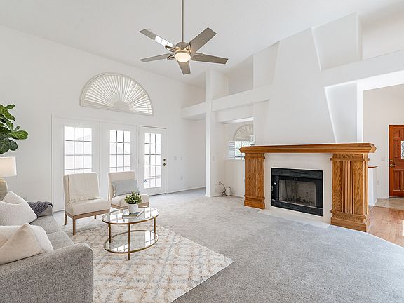 Family living room with vaulted ceiling neutral palette and working fireplace.