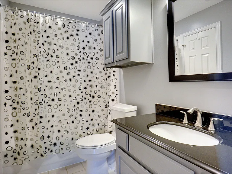 Bathroom featuring a vanity with an undermount sink, dark countertop, and brushed nickel faucet
