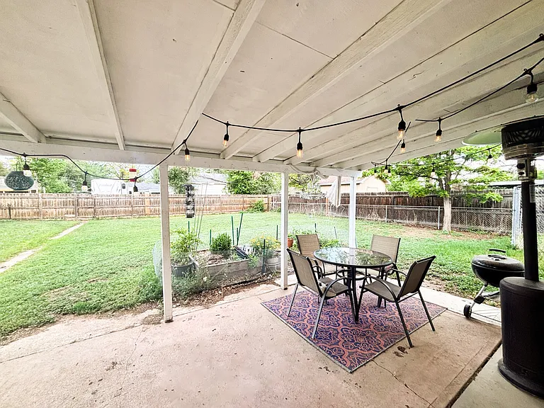 Covered patio and fenced backyard in springtime