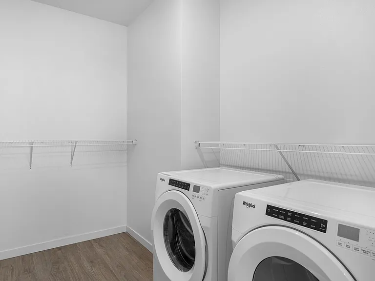 Modern laundry room with sleek washer and dryer, featuring stylish open shelving and inviting wood flooring. Modern laundry room with sleek washer and dryer, featuring stylish open shelving and inviting wood flooring.