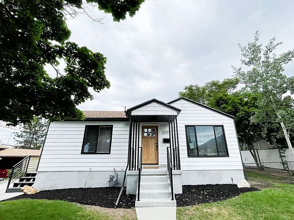 Front exterior of the home with side stairs access shown on left from detached garage and driveway to the side kitchen door. Fencing shown on right separating front and back yards.