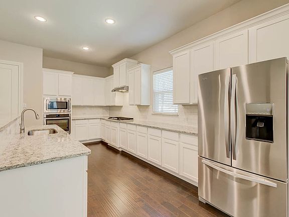 Elegant white kitchen fully equipped with stainless steel appliances.