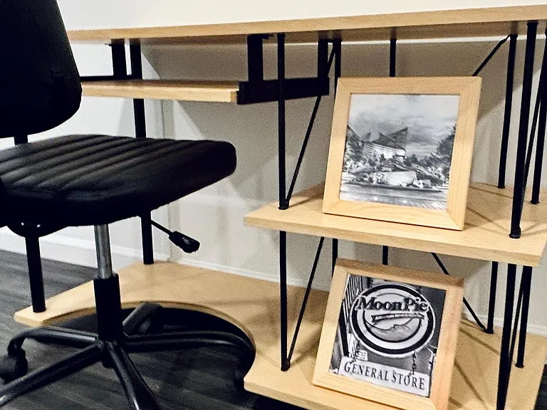 Compact work nook with a sturdy desk, shelving for storage or decor, and space for a rolling office chair.
