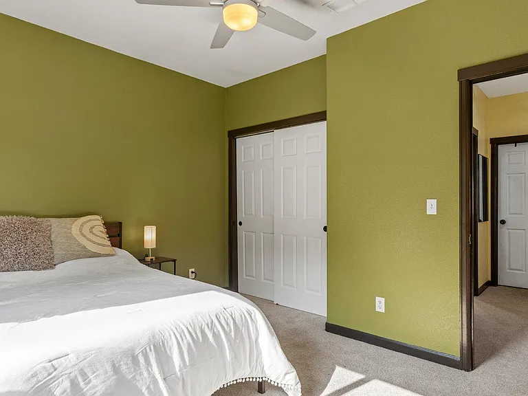 Carpeted bedroom with ceiling fan, sliding closet doors, and space for a full/queen bed plus a nightstand.
