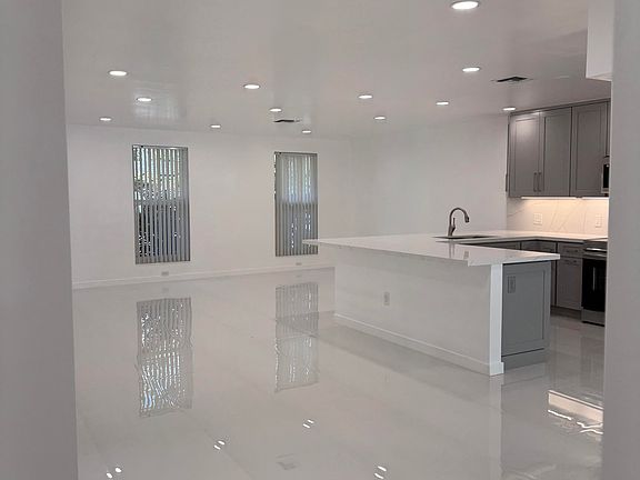 A view of the open lay-out, family, dining, living room, kitchen with quartz counter-tops and all new sparkling white 24 inch x 24 inch tile floors throughout.