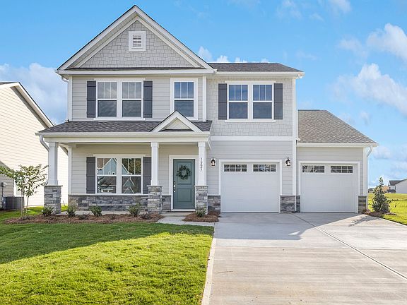 A large white house with a large driveway in front of it.