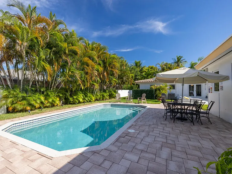 Double sized private fully fenced lot with patio, outdoor dining table, and heated pool.