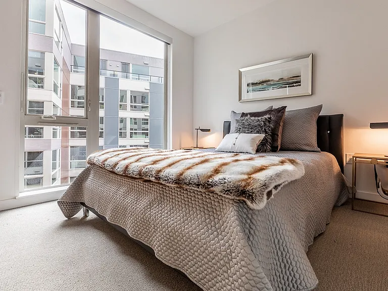 Bedroom with Floor-to-Ceiling Window and Framed Wall Art Above Bed