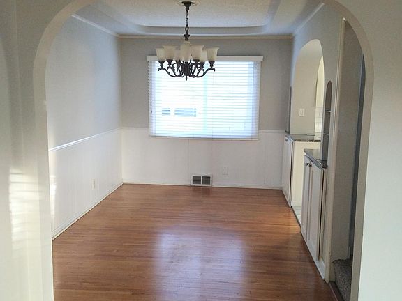 Dining room fits full size table plus a display cabinet. Hardwood floors, arched doorways, paneling and coved ceilings.