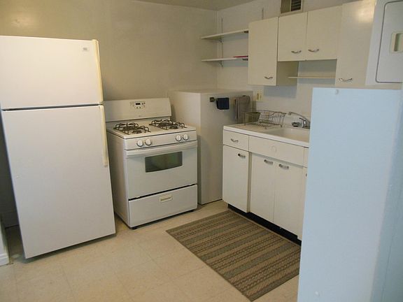 Kitchen: refrigerator, gas range, storage cupboard to left of refrigerator