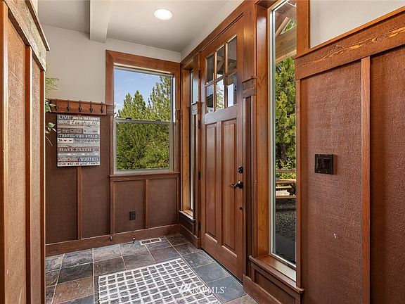 The entry with slate flooring, solid wood doors & millwork and wood wainscoting.