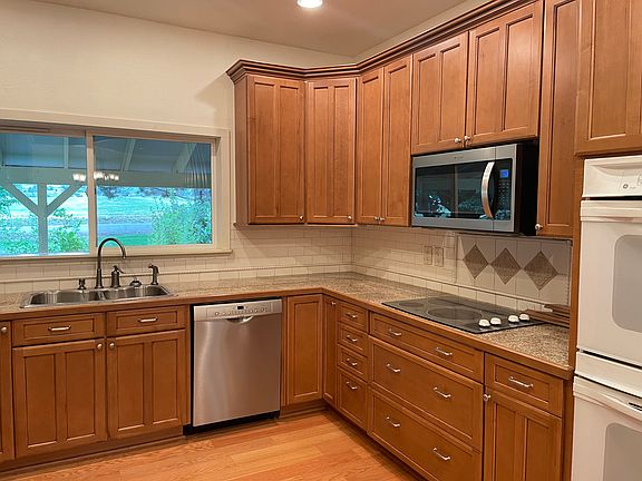 Large country kitchen with upscale cabinets with pull out drawers, granite counter tops with Italian tiled back splash, cook top, double ovens. Appliances are top brands. Hardwood flooring completes this dream kitchen.