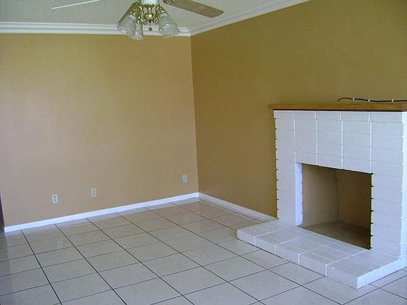 Large living room with fireplace, ceiling fan and tile floor