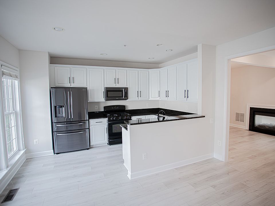 Modern Sleek Kitchen featuring black granite countertops, white cabinets and updated stainless steel appliances. Gas stove and functional fridge