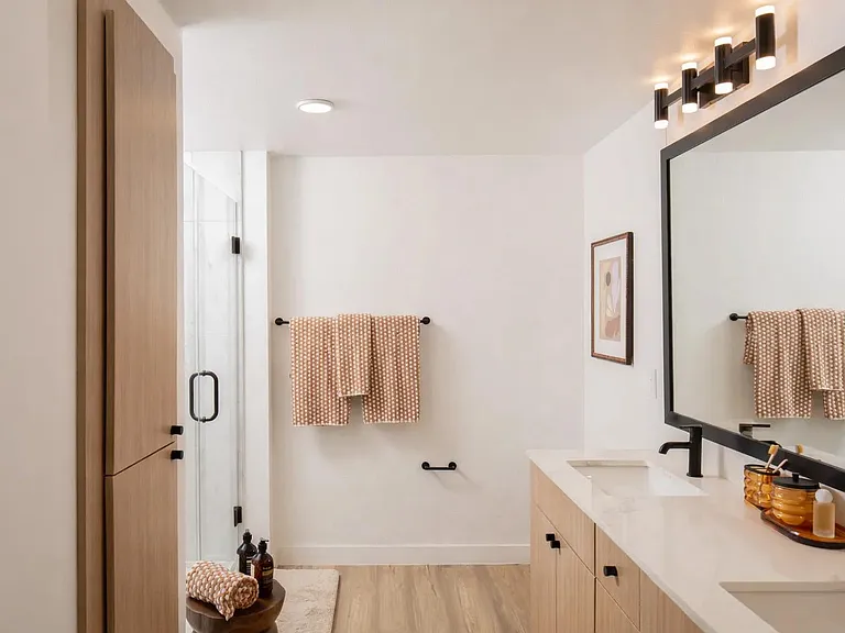 A refined primary bath with warm wood cabinetry, matte black fixtures, and clean lines for a polished, everyday routine.