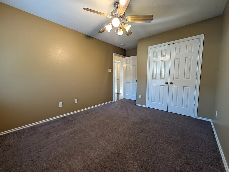 A second angle of Bedroom 3, showcasing the extensive closet space with two sets of double doors and the room's functional layout.