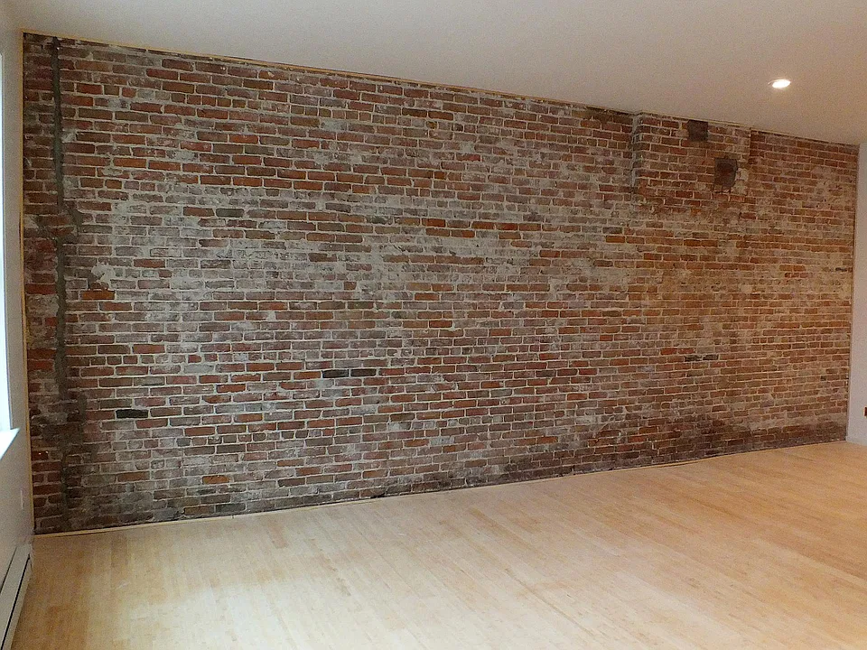 Large living area with high ceiling and exposed brick wall. Great Sunlight.