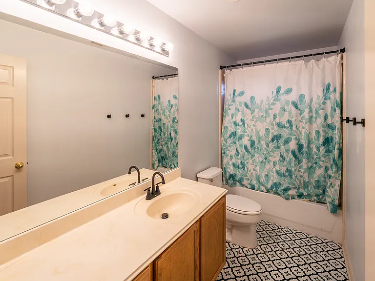 Stylish Second Bath: A beautifully maintained full bathroom featuring a large vanity with ample storage, clean modern fixtures, a tub/shower combo, and an eye-catching geometric patterned tile floor.