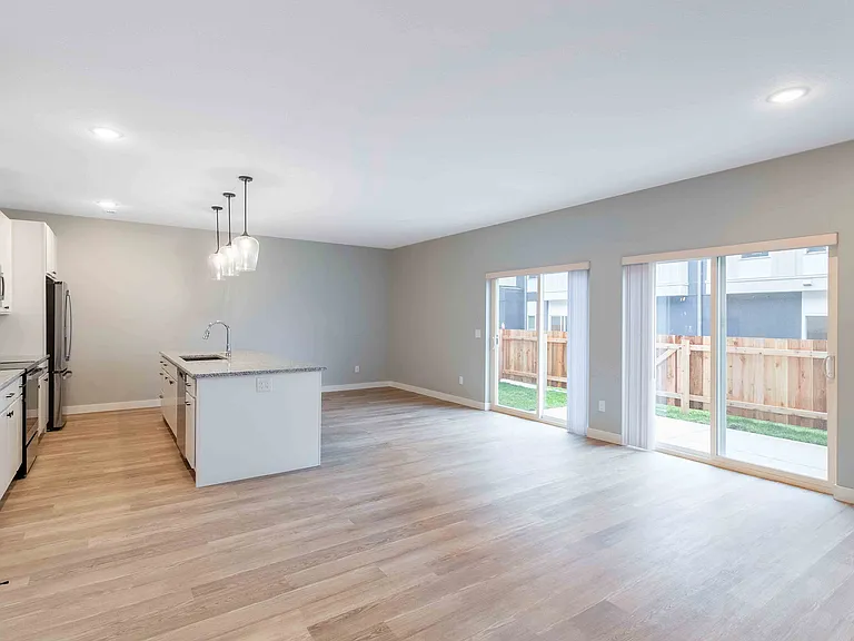 Bright and airy kitchen with granite island, modern fixtures, and expansive sliding glass doors leading to a private patio.