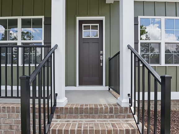 Front porch of The Charles in Poplar Village with brick steps, black railings, and a brown door with