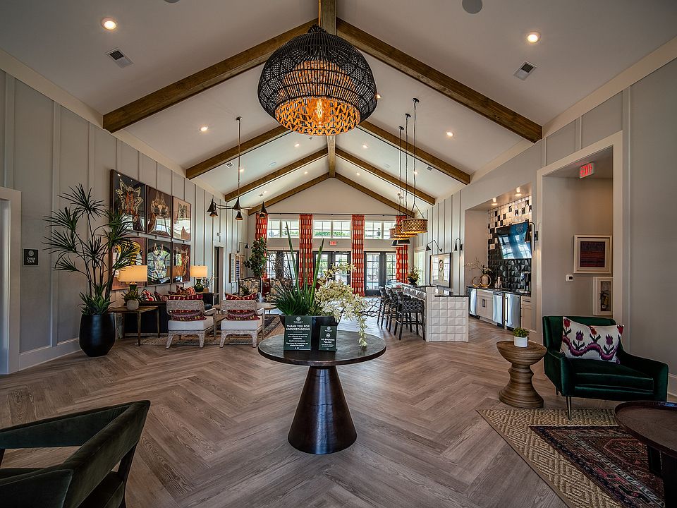 Spacious clubhouse with vaulted ceilings, elegant seating area, modern decor, and vibrant natural lighting.