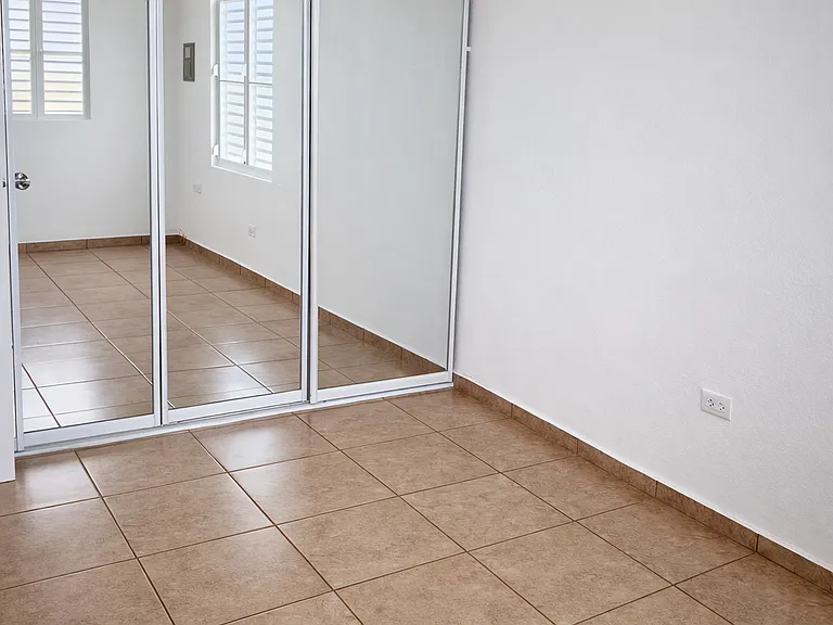 Spacious bedroom featuring large floor-to-ceiling mirrored closets.