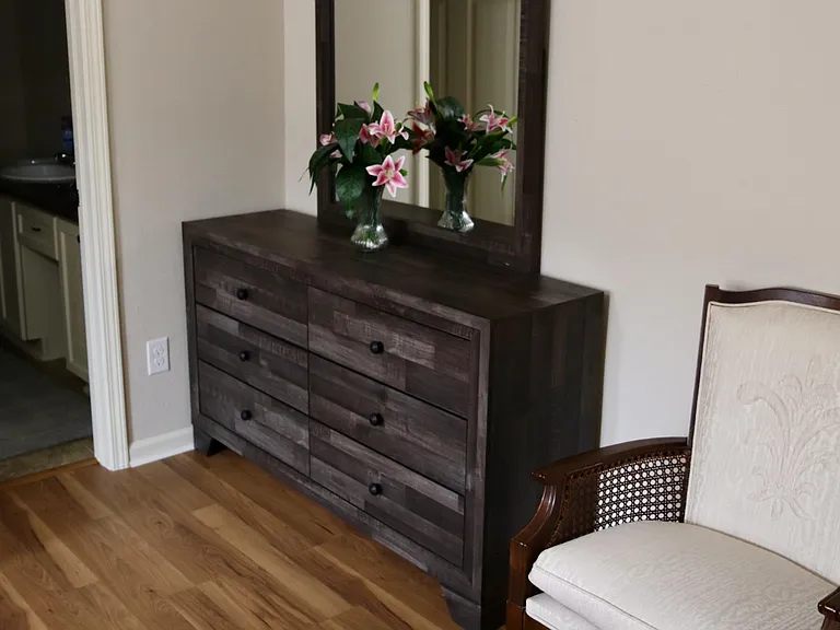 Entry area with hardwood floors, a wide dresser for storage, and a mirror accentideal as a drop zone near the bath.