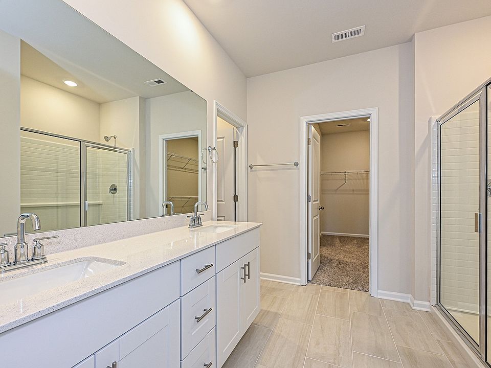 The primary bathroom boasts a dual-sink vanity and modern walk-in shower.
