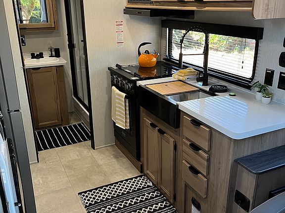 Kitchen with double sided sink with cutting board and dry rack, pull spray nozzle and oven and three burner top.
