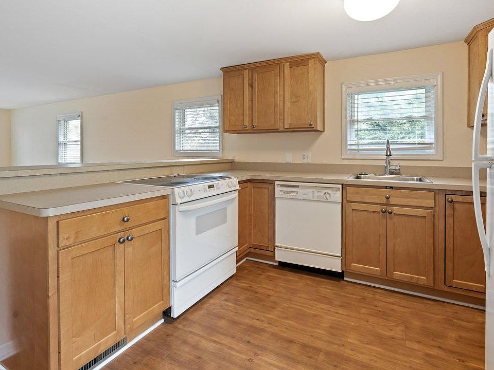 White kitchen appliances including electric stove, dishwasher and fridge. Plenty of cabinetry.