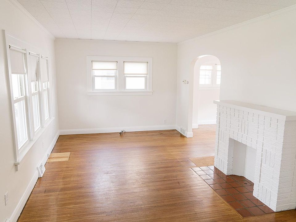 Living room featuring lots of windows, archways, and hardwood floors