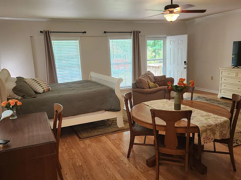 Spacious furnished studio-style room with bed, dining nook, lounge seating, and direct exterior access for easy comings and g