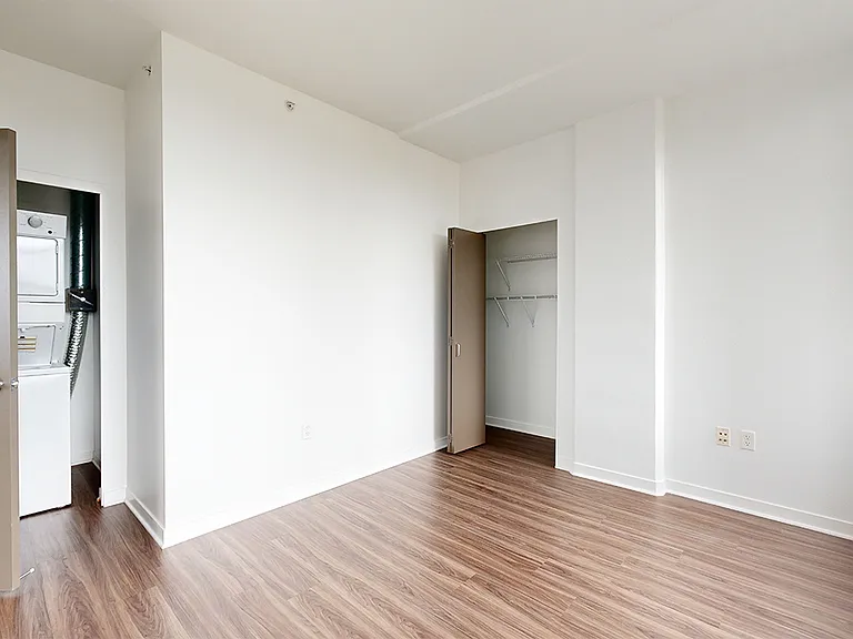 Spacious apartment bedroom with wood-style flooring.