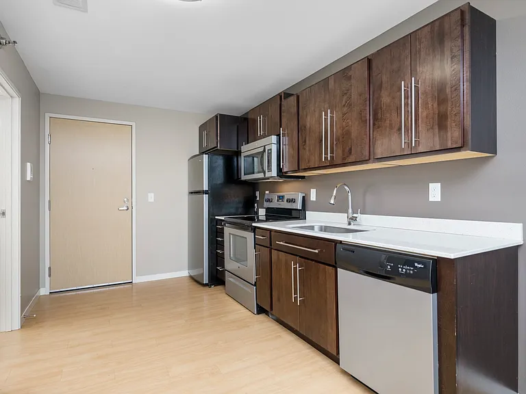 Modern kitchen with sleek wooden cabinets, stainless steel appliances, and bright laminate flooring. Modern kitchen with sleek wooden cabinets, stainless steel appliances, and bright laminate flooring.